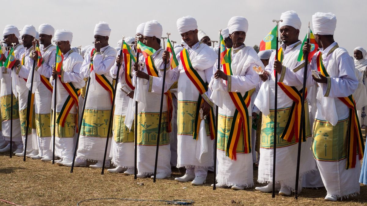 Orthodox priests in white robes and sashes in the colours of the flag at Timkat